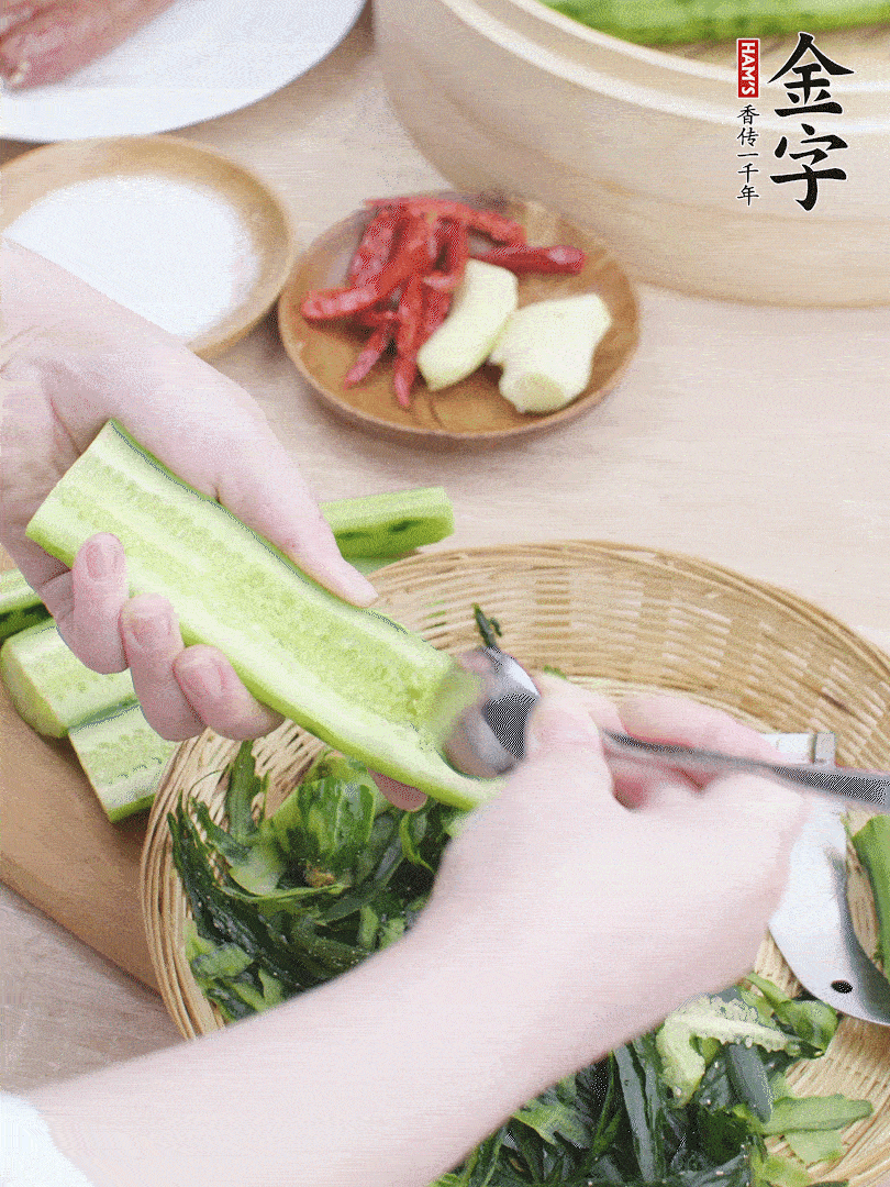黃瓜削皮，對半切開，勺子挖去內(nèi)瓤，斜刀切片。青蒜斜刀切段。